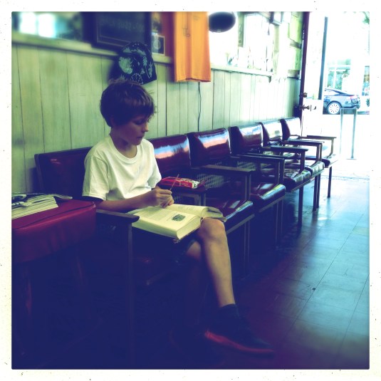 Flynn at the barber shop with his book while Dad gets his hair cut